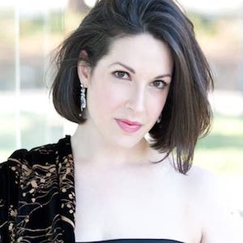Headshot of Leah wearing a green formal dress with a dark, gold-speckled shawl over her shoulders.